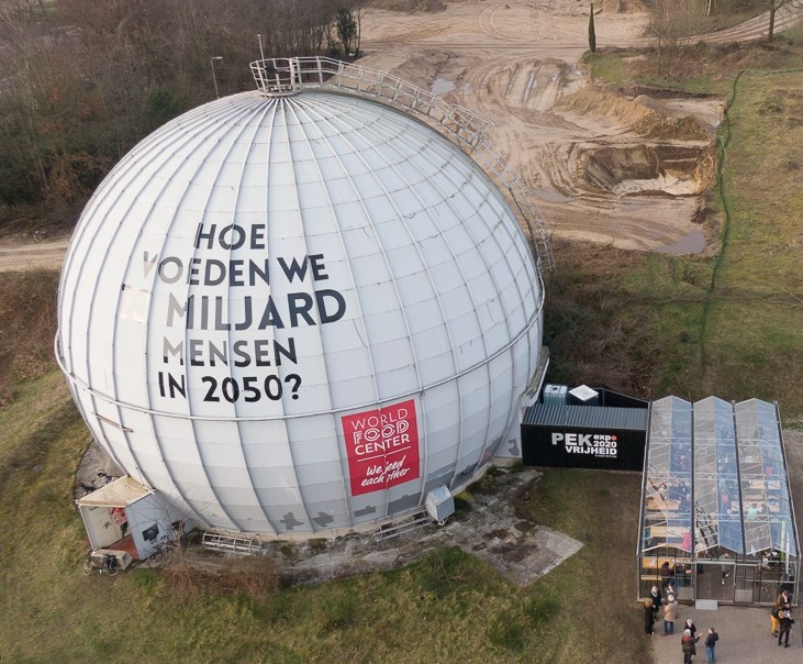 Luchtfoto van de Stingerlbol met daarop de tekst "Hoe voeden we 10 miljard mensen in 2050" en logo van World Food Center